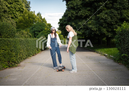 Friends enjoy a sunny afternoon skating and laughing in the park 130028111