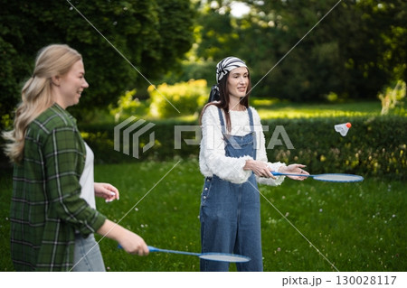 Two friends enjoy a playful afternoon of badminton in a lush green park Two friends enjoy a playful afternoon of badminton in a lush green park 130028117