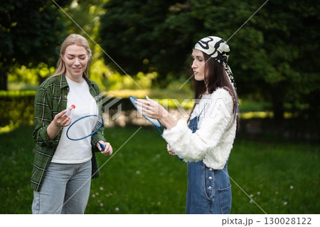 Friends enjoying a lively badminton match in a sunny green park Friends enjoying a lively badminton match in a sunny green park 130028122
