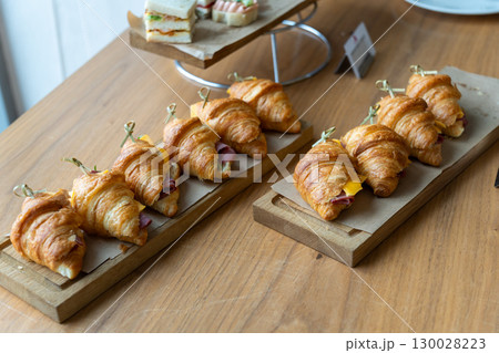 Freshly baked ham and cheese croissants arranged on a rustic wooden board Freshly baked ham and cheese croissants arranged on a rustic wooden board 130028223