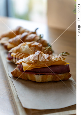Freshly baked ham and cheese croissants arranged on a rustic wooden board 130028224