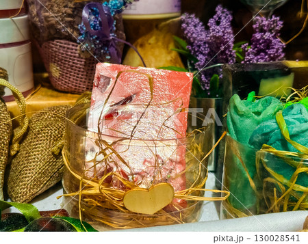 Handmade soap with decorative elements in a transparent container with straw. Image represents craft, wellness, fragrance and artisanal product display. 130028541