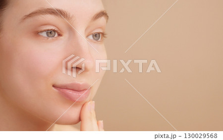Close-up portrait happy attractive young woman apply facial oil serum or moisturizer. The concept of skincare advertising, beauty routine. Young girl's face on a light studio background. Copy space Close-up portrait happy attractive young woman apply facial oil serum or moisturizer. The concept of skincare advertising, beauty routine. Young girl's face on a light studio background. Copy space 130029568