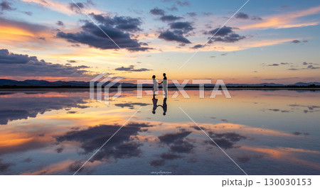 鏡のような塩湖で手をつなぐ二人 130030153