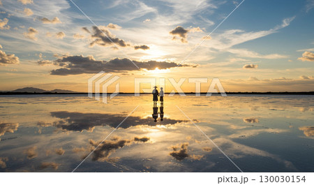 鏡のような塩湖で手をつなぐ二人 130030154