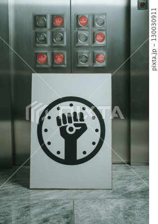 Protest Sign with Clock Icon in Front of Elevator Buttons 130030911