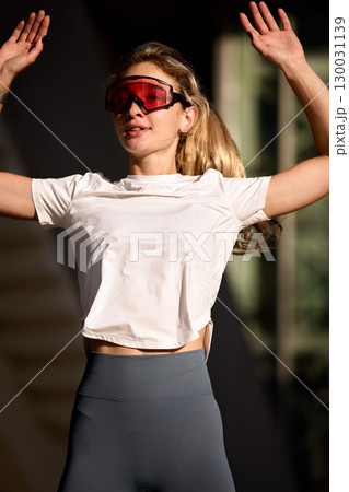 Woman exercising outdoors wearing stylish activewear and sunglasses on a sunny day 130031139