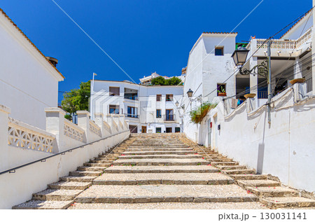 Altea old town narrow street with staircase steps, typical white houses traditional buildings in sunny day, Altea city historical centre Casco Antiguo, Alicante province, Valencian Community, Spain 130031141