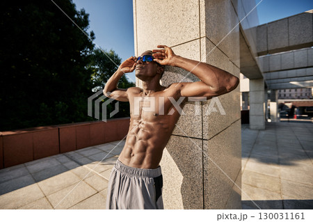 Athletic man posing outdoors against a modern building during daytime Athletic man posing outdoors against a modern building during daytime 130031161