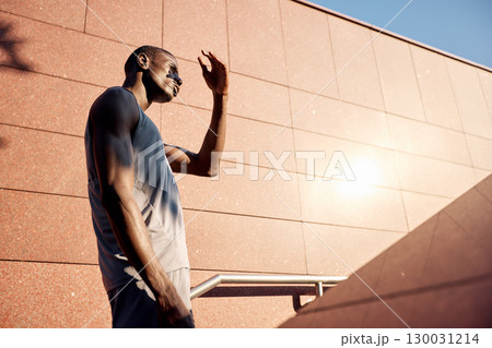 Athletic individual shielding eyes from sun in urban environment 130031214
