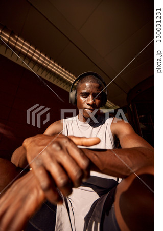 Focused athlete wearing headphones while enjoying a moment of rest outdoors 130031231