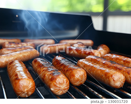 Grilled sausages sizzling on barbecue grill with smoke rising 130031720