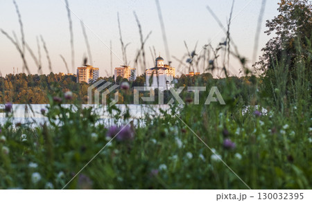 Sun is setting by the lake with city buildings and church on the background Sun is setting by the lake with city buildings and church on the background 130032395
