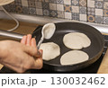 Woman pours pancake dough in to the frying pan 130032462