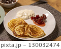 Freshly baked pancakes on the ceramic plate next to the strawberry jam and sour cream 130032474