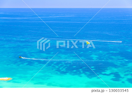 Parasailing in sea, motorboat powerboat with attached parachute on azure turquoise water of Mediterranean Sea, water sport on summer vacation, motor boat, Alicante bay aerial view, Spain 130033545