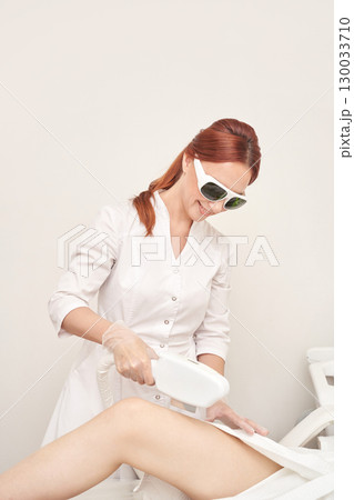 Caucasian female performing laser hair removal procedure in clinic setting Caucasian female performing laser hair removal procedure in clinic setting 130033710