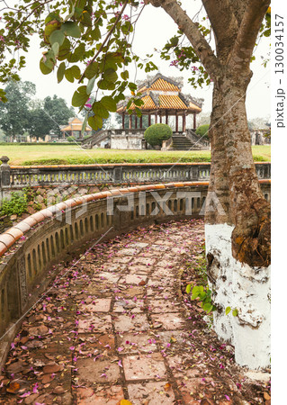 Curved stone path with scattered flower petals leading to traditional pavilion in Hue Imperial City Vietnam 130034157