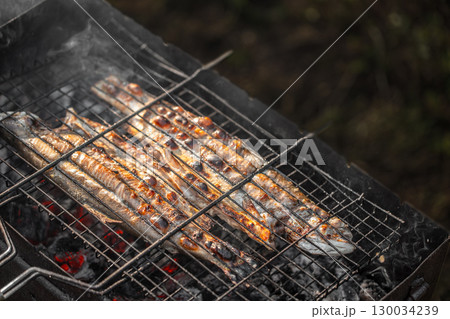 Grilled fish cooking on barbecue grill over hot coals outdoors. top view. copy space 130034239
