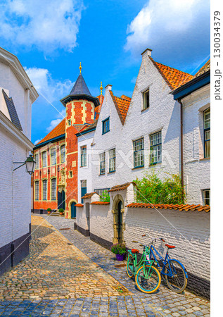 Beguinage Courtrai, Begijnhof van Kortrijk with white houses, bicycles near wall on narrow paving stone street in Kortrijk city historical centre, vertical view, belgium landmark, Belgium Beguinage Courtrai, Begijnhof van Kortrijk with white houses, bicycles near wall on narrow paving stone street in Kortrijk city historical centre, vertical view, belgium landmark, Belgium 130034379