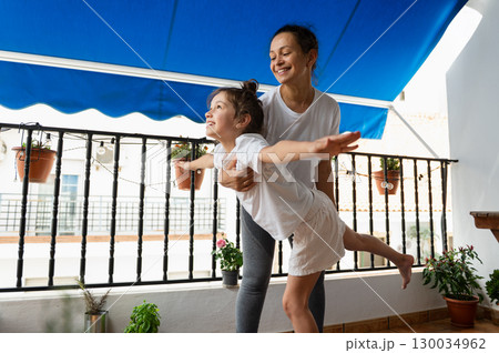 Happy Mother and Daughter Enjoying Playtime on a Sunny Home Balcony Happy Mother and Daughter Enjoying Playtime on a Sunny Home Balcony 130034962