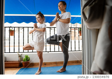 Mother and Daughter Practicing Yoga Together on a Balcony Mother and Daughter Practicing Yoga Together on a Balcony 130034970