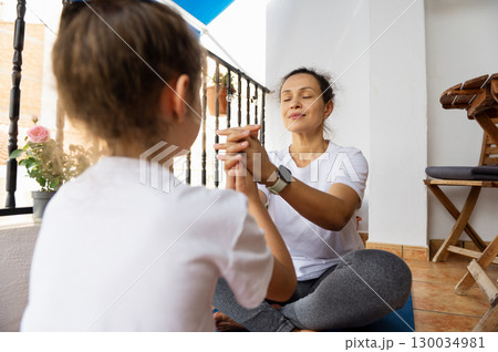 Mother and Daughter Practicing Yoga at Home on a Peaceful Morning 130034981