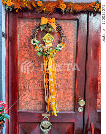 Closeup of floral wreath with ribbons on a decorated door. Tradition, celebration, design and lifestyle in a European cultural setting. 130035073