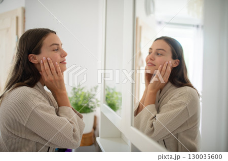 Beautiful woman checking her skin during skincare routine. Morning ritual. Beautiful woman checking her skin during skincare routine. Morning ritual. 130035600