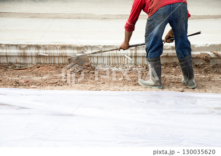 Workers are using shovels to level the ground before pouring concrete at a road construction site. Workers are using shovels to level the ground before pouring concrete at a road construction site. 130035620
