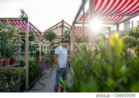 Garden store employee taking care of plants. Garden store employee taking care of plants. 130035630