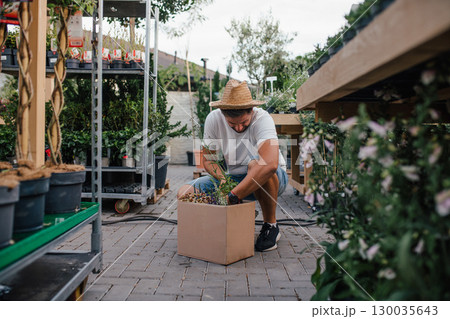 Customer looking at flowers in box at plant nursery, shopping for garden plants. 130035643