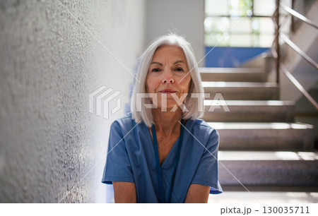 Exhausted nurse resting on stairwell during hospital shift Exhausted nurse resting on stairwell during hospital shift 130035711