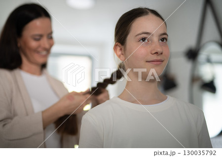 Mother braiding daughters thick hair in bathroom. Mother braiding daughters thick hair in bathroom. 130035792