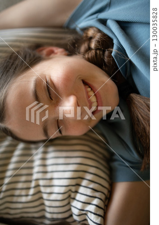 Teenage girl lying on pillow with gentle smile Teenage girl lying on pillow with gentle smile 130035828