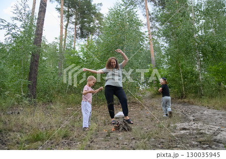 Family Roasting Marshmallows Over Campfire in Forest 130035945