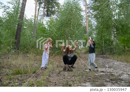 Family Roasting Marshmallows Over Campfire in Forest 130035947