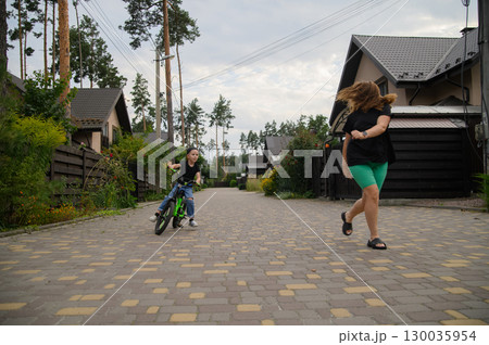 Mother and Son Playing Outdoors Boy Riding Bicycle in Suburban Neighborhood 130035954