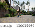 Mother Pushing Son on Skateboard in Suburban Neighborhood Street 130035969