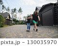 Mother Pushing Son on Skateboard in Suburban Neighborhood Street 130035970