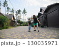 Mother Pushing Son on Skateboard in Suburban Neighborhood Street 130035971