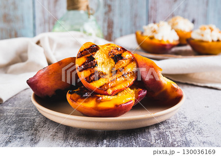 Delicious grilled peach halves on a plate on the table closeup 130036169