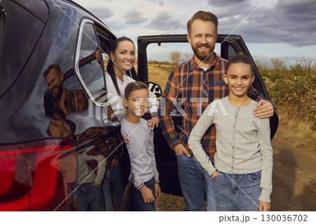Happy mother, father and children outside their automobile during a family car trip 130036702