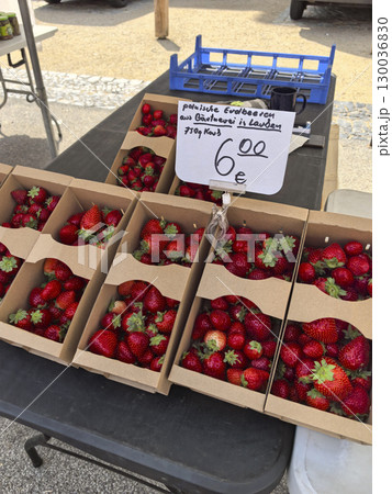 Freshly picked strawberries at a vibrant market stall in sunny weather 130036830