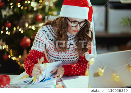 business woman in green office with Christmas tree working 130036839