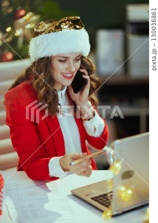 smiling talking on phone in green office with Christmas tree smiling talking on phone in green office with Christmas tree 130036861