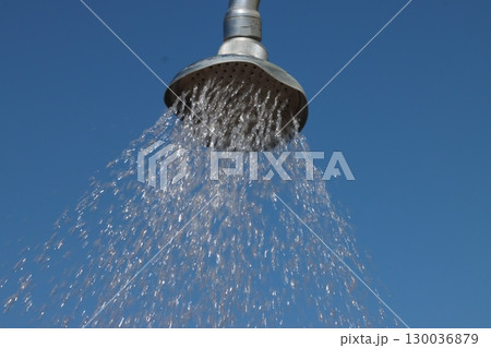 Shower head pouring water against blue sky on sunny day Shower head pouring water against blue sky on sunny day 130036879