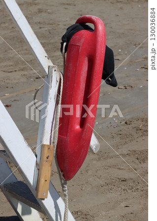 Red rescue buoy hanging on lifeguard chair at beach 130036884