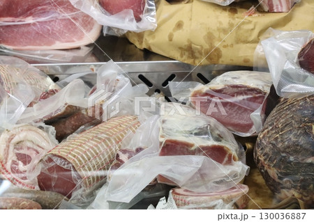 Vacuum packed cured meats displayed on market stall 130036887