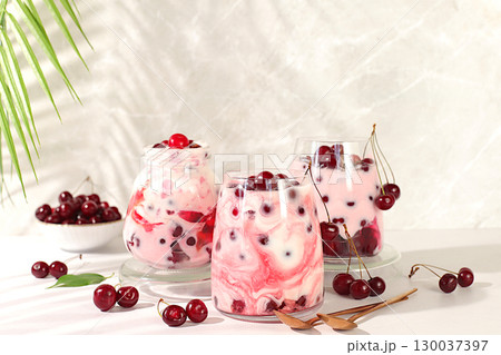 Fruit yogurt with cherries and fresh cow cream for healthy nutrition in a glass on an elegant table. Healthy breakfast with ingredients, kitchen background. Natural food and detox diet concept 130037397